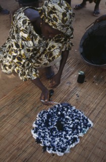 GAMBIA, Work, Woman using indigo coloured dye to tie dye fabric.