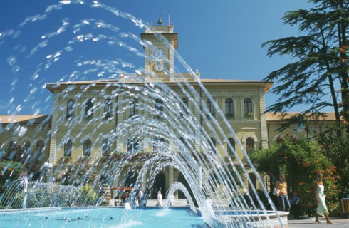 ITALY, Emilia-Romagna, Cattolica, Fountains in town square with building with clock tower behind.