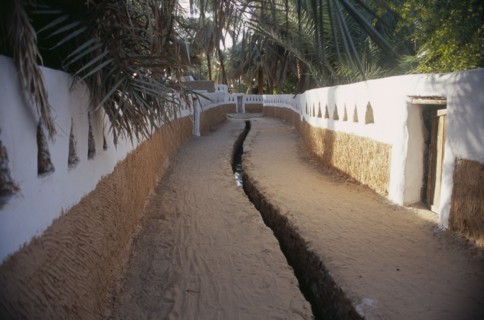 LIBYA, Ghadames, Deep irrigation channel through street between walls partly painted white with