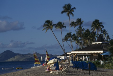 WEST INDIES, Nevis, View along beach with sails and sunbeds beside beach bars of the Four Seasons