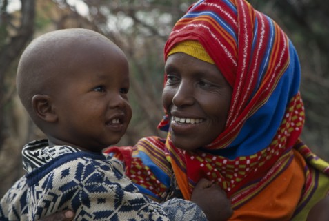 SOMALIA, Near Hargeisa, Portrait of mother wearing colourful headscarf holding and looking at her