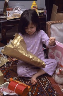 FESTIVALS, Christmas, Presents, Five year old girl sitting on the floor opening her Christmas