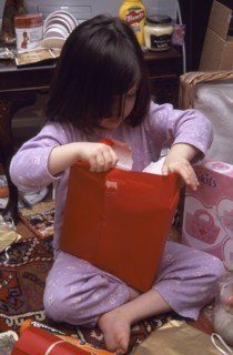FESTIVALS, Christmas, Presents, Five year old girl sitting on the floor opening her Christmas