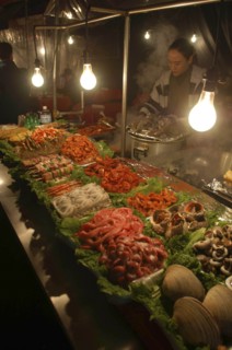 KOREA, Seoul, "Namdaemun Market on a cold December night with a woman cooking behind trays of fresh