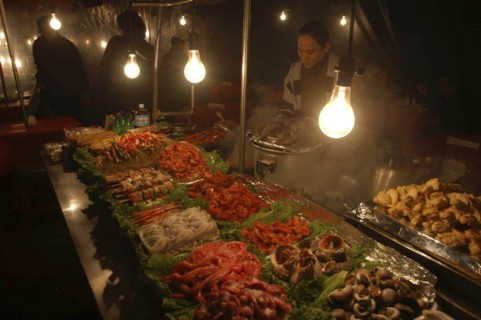 KOREA, Seoul, "Namdaemun Market on a cold December night with a woman cooking behind trays of fresh