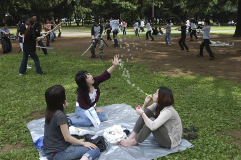 JAPAN, Honshu, Tokyo, "Harajuku. Yoyogi Park. Miki Tomiyoka, aged 23, blows bubbles for two friends