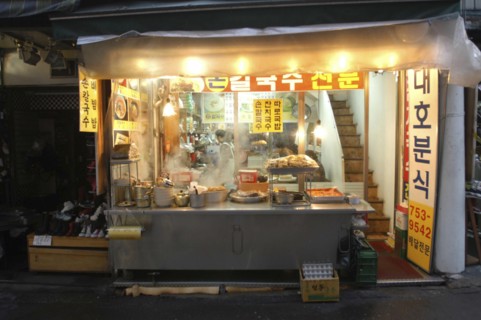 KOREA, Seoul, Namdaemun Market at night in December. Streetside open restaurant with staff and