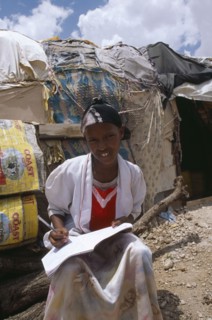 SOMALILAND, Hargeisa, Girl doing homework outside hut in Kandahar IDP camp.