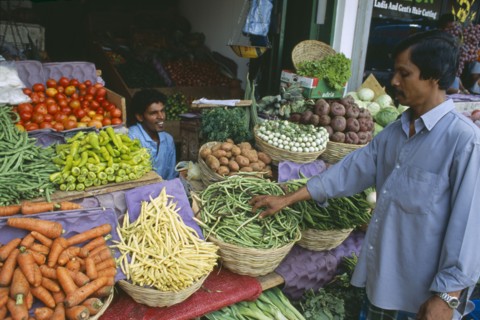 SRI LANKA, Colombo, Pettah District. Customer at a market stall selling vegetables