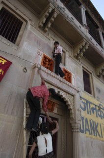 INDIA, Uttar Pradesh, Varanasi , Deep Diwali Festival with teenage boys climbing a doorway to