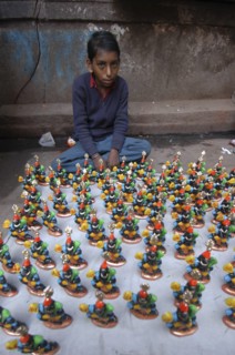 INDIA, Uttar Pradesh, Varanasi, Young boy selling figurines of Kala Bhairava outside Kala Bhairava