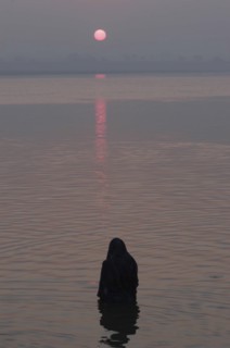 INDIA, Uttar Pradesh, Varanasi, Asi Ghat. A Hindu man baths in the Ganges River with the early