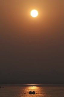INDIA, Uttar Pradesh, Varanasi, Ganges River at dawn with rowing boat silhouetted against warm