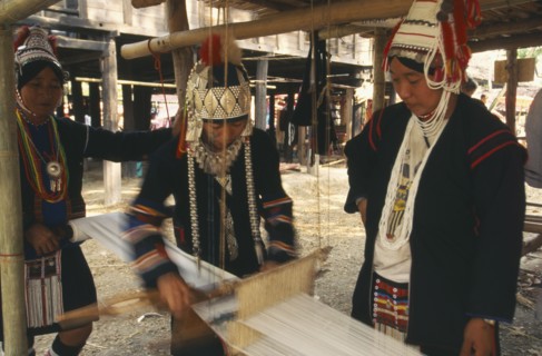 THAILAND, Chiang Mai, Akha woman weaving cloth on an Akha loom as other women look on