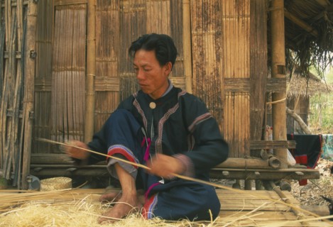 THAILAND, Chiang Mai Province, Red Lahu man shaving bamboo into strips