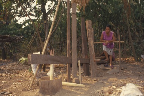 THAILAND, Chiang Mai Province, Mueng Keurt, Woman grinding coffee seeds with a foot powered mill to