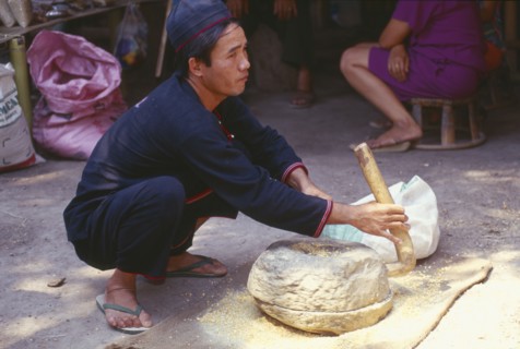 THAILAND, Chiang Mai Province, Yao man grinding corn in a stone hand grinder