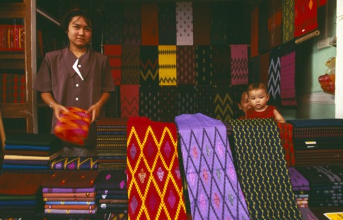 MYANMAR, Kachin State, Myitkyina, Kachin woman selling sarongs and other textiles at the market