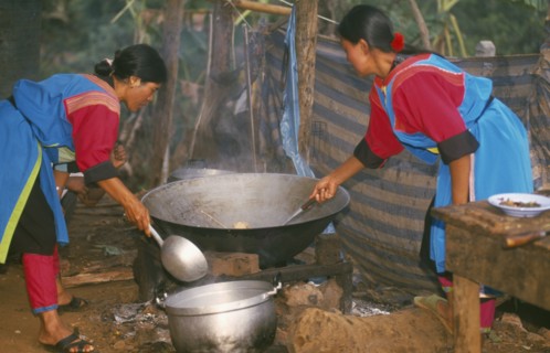 THAILAND, Chiang Rai Province, Huai Khrai, Lisu women stir frying a meal in a large wok for New