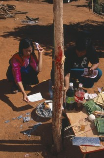 THAILAND, Chiang Mai Province, Bahn Mae Phaem, Lisu girl and man burning imitation money beside New