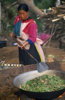 THAILAND, Chiang Rai Province, Huai Khrai, Lisu woman stir frying meal in large wok for New Year