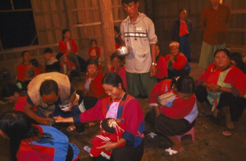THAILAND, Chiang Rai Province, Doi Lan, Lisu shaman spraying supplicants hand at healing ceremony