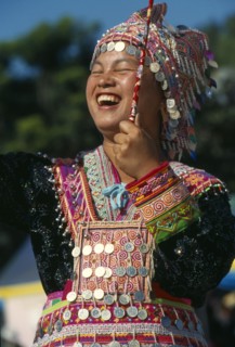 THAILAND, Chiang Mai, Hmong New Year. Young blue Hmong woman in her New Year finery laughing