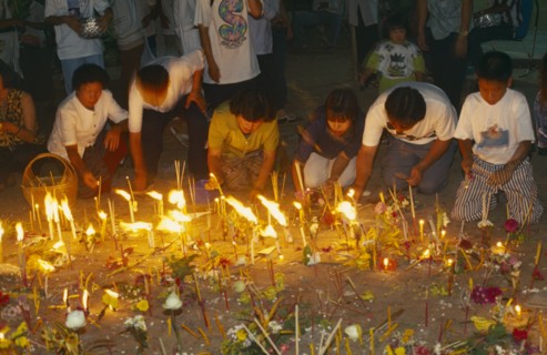 THAILAND, Chiang Mai, Wat Jedi Luang, Inthakhin Ceremony. People with offerings of flowers candles