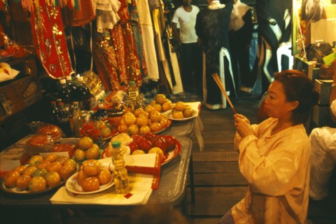 THAILAND, Chiang Mai, Female performer at the Chinese Opera offering joss sticks in prayer