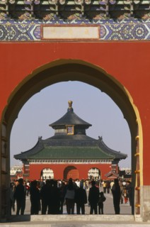 CHINA, Beijing, Temple of Heaven.  Temple and tourists framed by red painted archway.