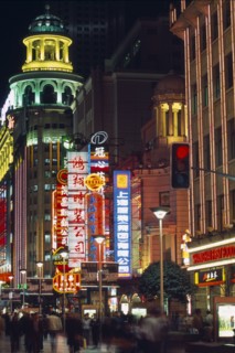 CHINA, Shanghai, Nanjing Road at night with illuminated neon signs and crowds of people in blurred