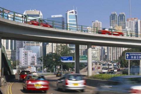 CHINA, Hong Kong, Elevated highway and traffic with city skyscrapers behind.