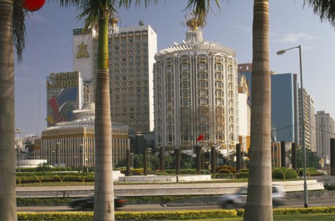 CHINA, Macau, Casino Lisboa.  Exterior framed by palm tree trunks in foreground.