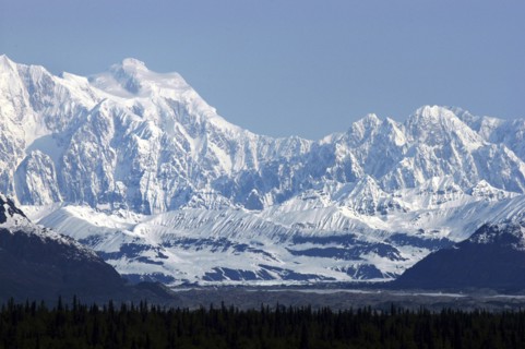 USA, Alaska, Snow covered mountain range seen over green treetops