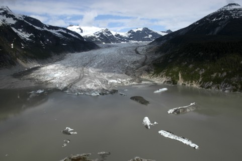 USA, Alaska, Juneau, View over murky waters and valley leading toward snowcapped mountain peaks