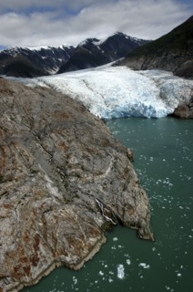 USA, Alaska, Tracy Arm Fjord, View over rocky edged waterway toward icy slope and mountain peaks