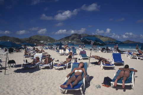 WEST INDIES, French Antilles, St Martin, Orient beach with people sunbathing on loungers