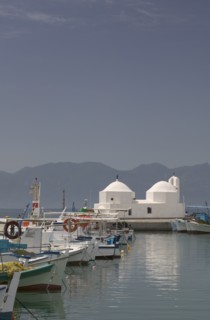 GREECE, Saronic Islands, Aegina, Fishing boats moored in Aegina Town next to a small white church