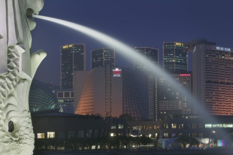 SINGAPORE, Merlion Park, Detail of the Merlion statue at dusk with the Marina Square Complex in the