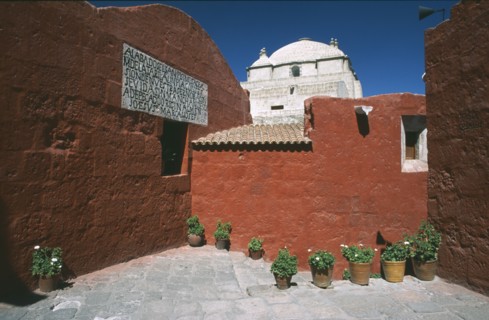 PERU, Arequipa, Alleyway with brightly coloured buildings and the white roof of the Monasterio de