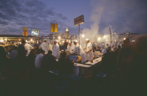 MOROCCO, Marrakesh, Djemaa el Fna. Food vendors serving up food to hungry customers seated around