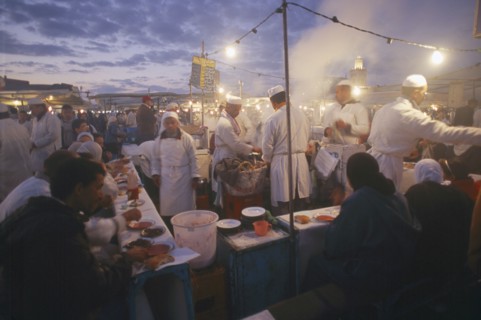 MOROCCO, Marrakesh, Djemaa el Fna. Food vendors serving up food to hungry customers seated around