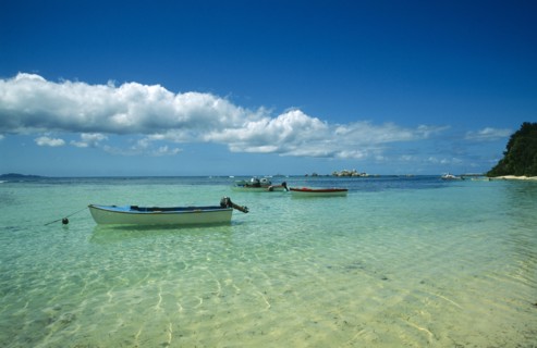 SEYCHELLES, La Digue, "Fishing boats moored in clear, shallow water near beach. "