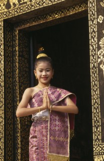 LAOS, Luang Prabang, Young girl dressed for New Year festivities framed in doorway of temple.