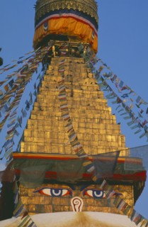 NEPAL, Kathmandu, Bodnath Stupa, Detail of spire of stupa with painted eyes and hung with prayer
