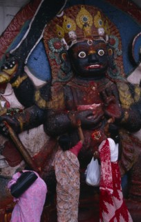NEPAL,  , Kathmandu, Women making offerings at the Kala Bhairab or black Shiva in Durbar Square