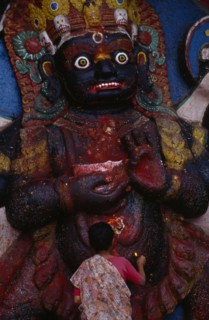 NEPAL,  , Kathmandu, Woman making offerings at the Kala Bhairab or black Shiva in Durbar Square