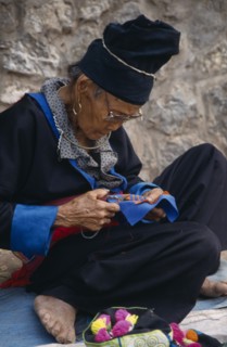 LAOS, Luang Prabang, Hmong woman embroidering traditional textile.