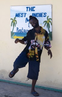 WEST INDIES, St Vincent & The Grenadines, Union Island, Man dancing beside a restaurant sign in