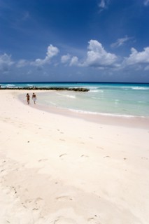 WEST INDIES, Barbados, Christ Church, Couple walking towards sea defences on Rockley Beach also